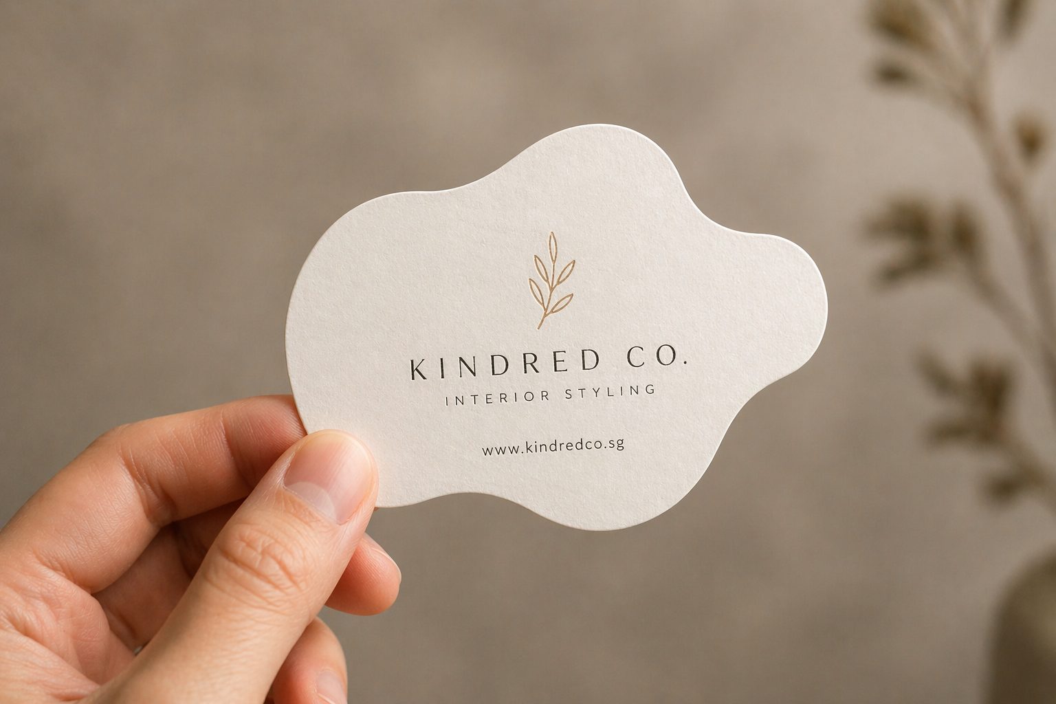 Die-cut business card with custom rounded shape held between fingers