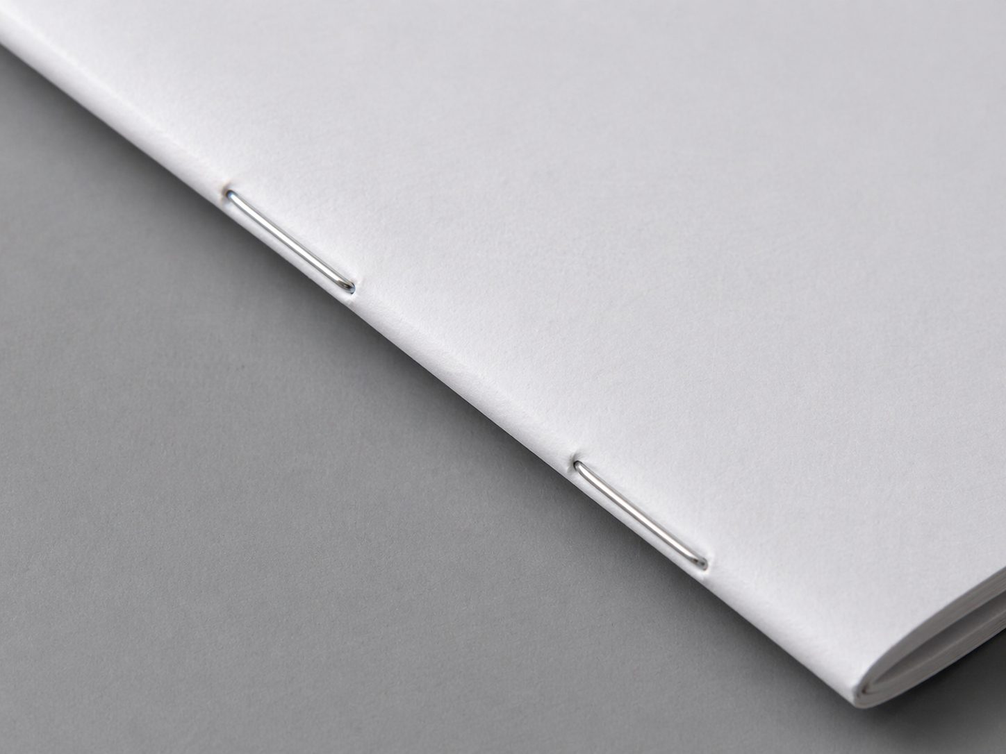 Close-up of saddle-stitch binding with two staples on the spine of a booklet